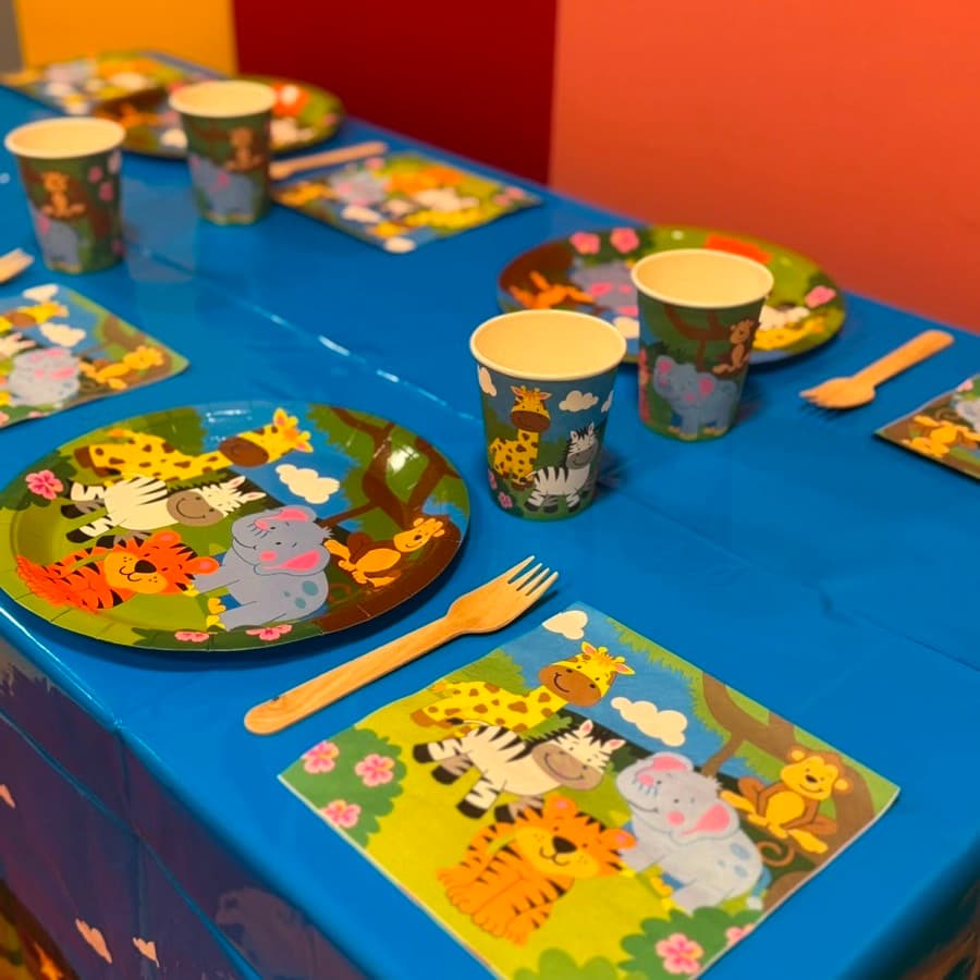 A party table set with friendly zoo animal plates, cups and napkins